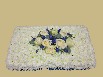 Blue & White Funeral Pillow - A traditional pillow-shaped funeral tribute of fresh white flowers, finished with an elegant arrangement of cream and blue blooms for a peaceful farewell.